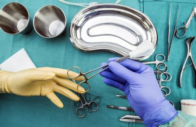 Surgeon working in operating room, hands with gloves holding scissors of suture and torundas